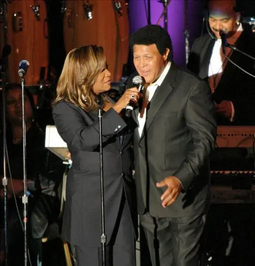 A man and woman sing into microphones.